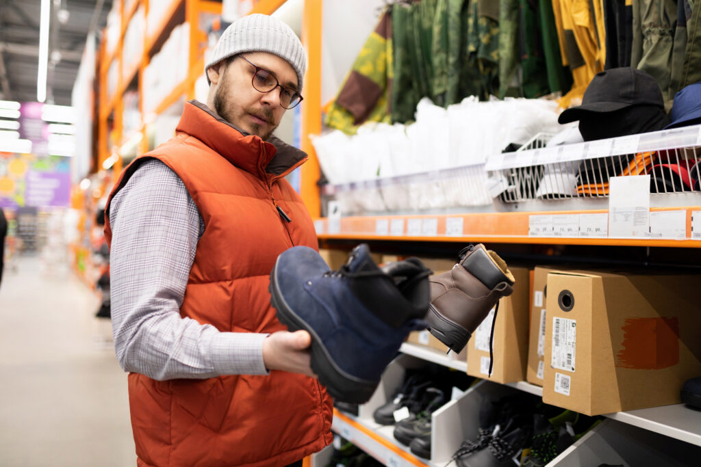 A man in a hardware store chooses safety footwear for construction work.
